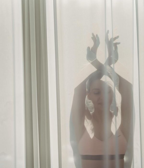 Woman performing a gentle cardio exercise in a bright, calm room.